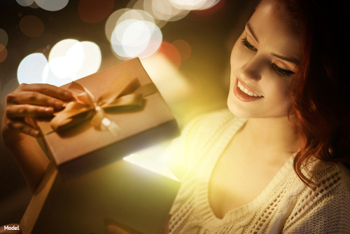 woman smiling, looking at Christmas present