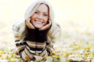 Woman laying in leaves, smiling